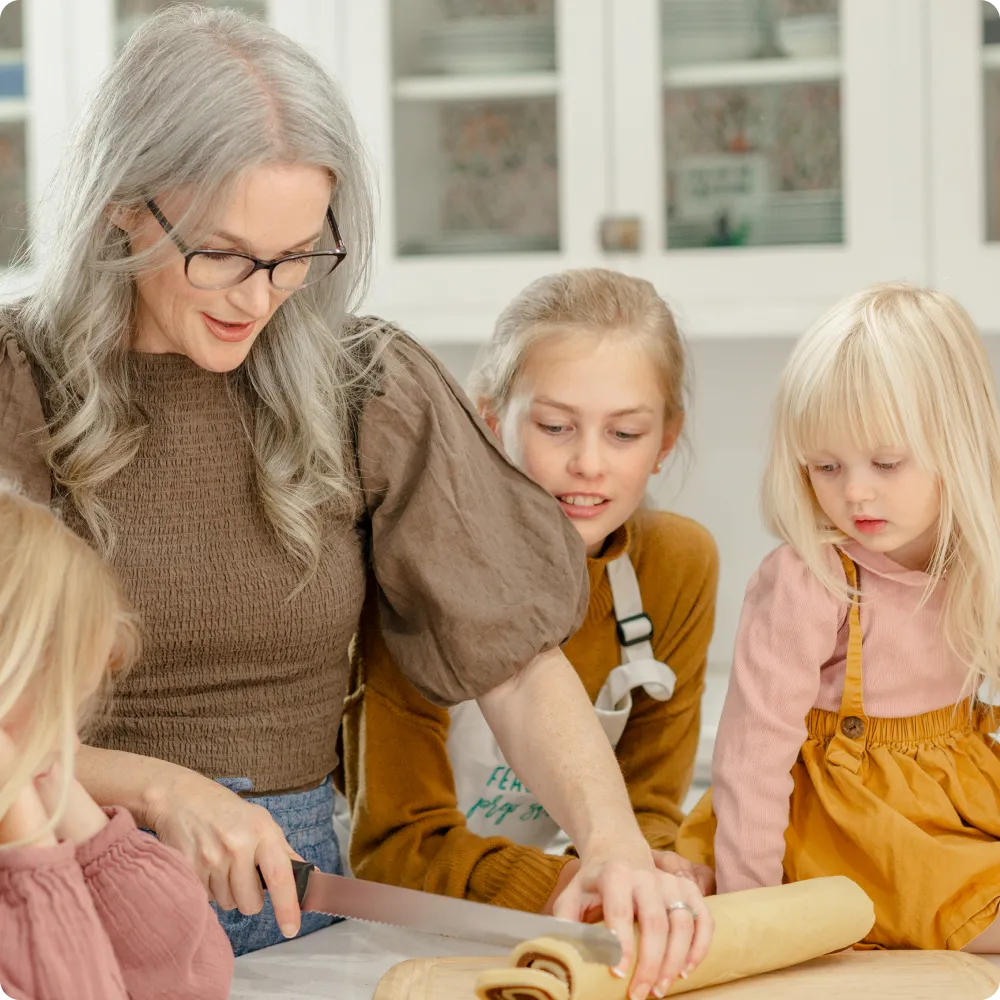 Kendra using membership recipe card to create a cinnamon roll alongside here three daughters at home