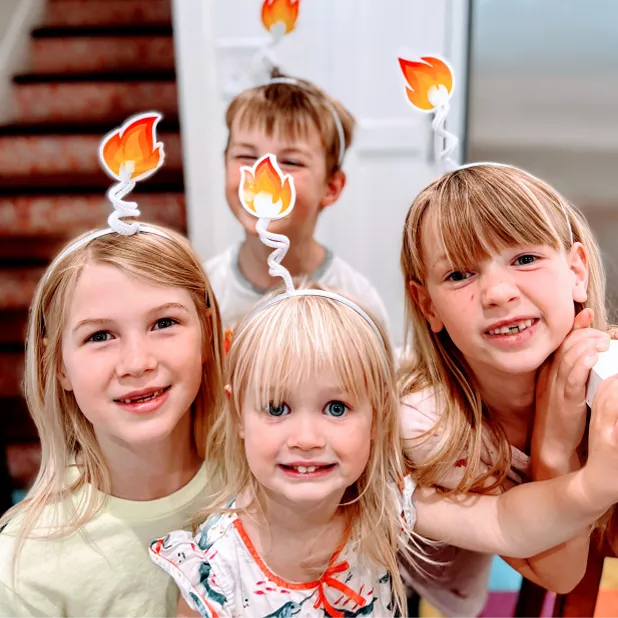 Four of Kendra’s children complete a membership activity resulting in them wearing headbands with a cut-out flame on top